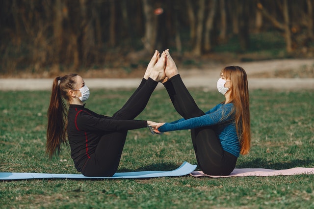 Two girls doing boat pose yoga at same time